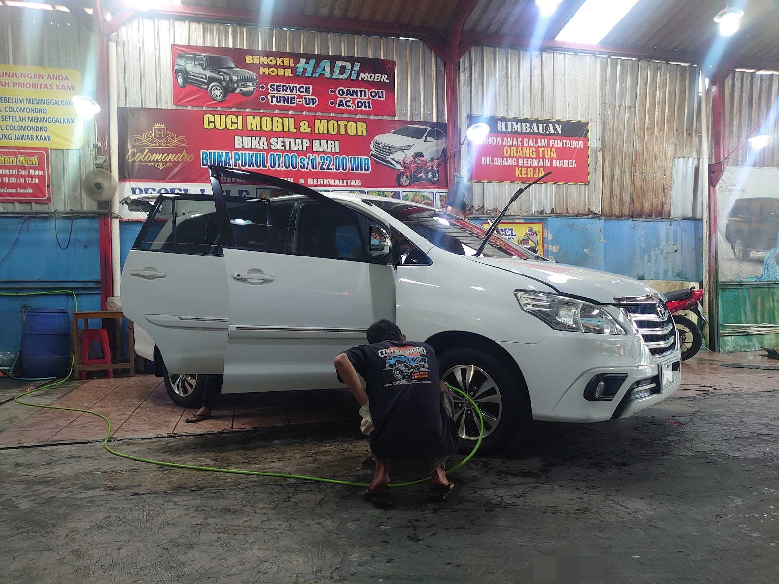 Petugas membersihkan roda mobil putih di area cuci