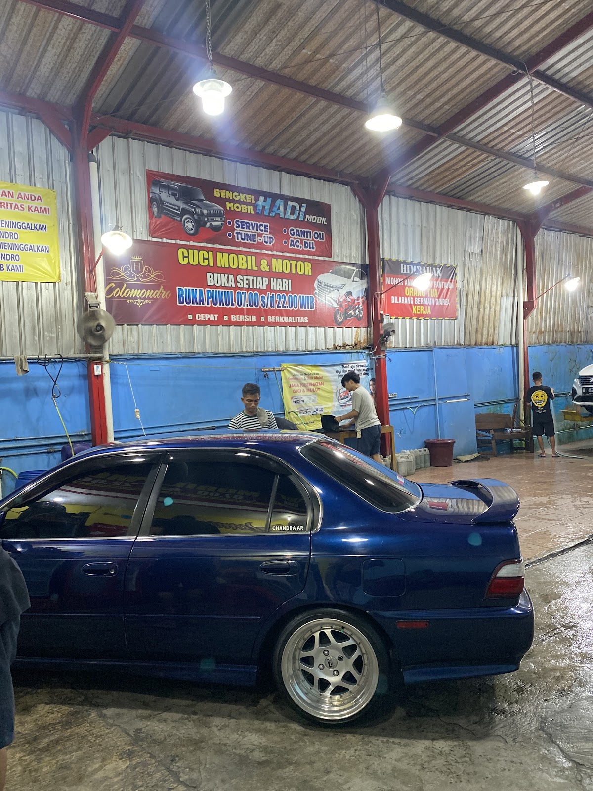 Mobil biru di area cuci dengan dinding biru dan atap tinggi