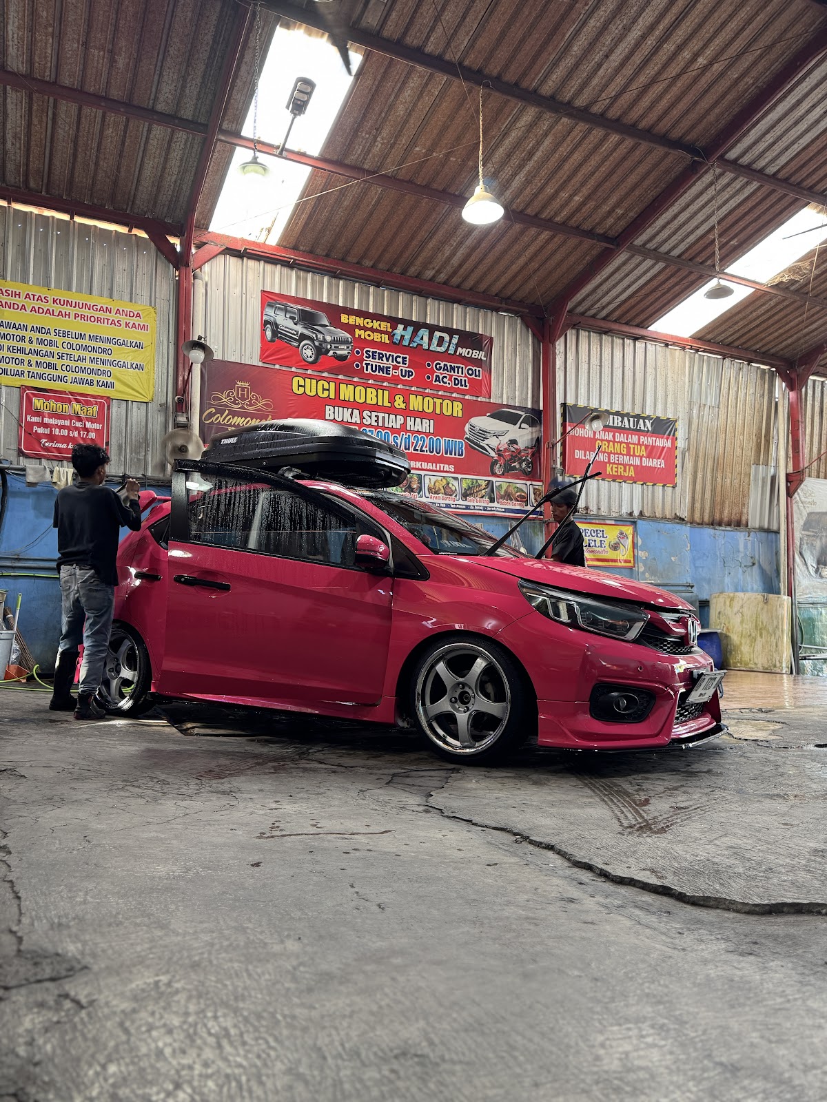 Mobil merah sedang dibersihkan di dalam area cuci beratap